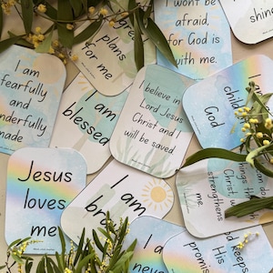 May include: A collection of inspirational cards with rounded corners, featuring pastel watercolor backgrounds and uplifting messages. The cards display phrases like "I am blessed" and "Jesus loves me," with floral accents.