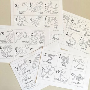 May include: A collection of alphabet flash cards with hand-drawn illustrations. Each card displays a letter alongside a corresponding image, such as an apple, bee, crab, frog, octopus, snake, and whale. The text "alphabet flash cards" is also visible.