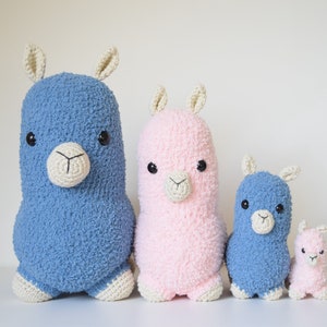 Op de afbeelding: Vier gehaakte lama knuffels in verschillende maten. De grootste lama is blauw, de op een na grootste is roze, de derde grootste is blauw en de kleinste is roze.