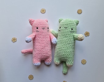 May include: Two crocheted cat toys, one pink and one green, with embroidered eyes and whiskers. The toys are holding hands and have a playful expression.
