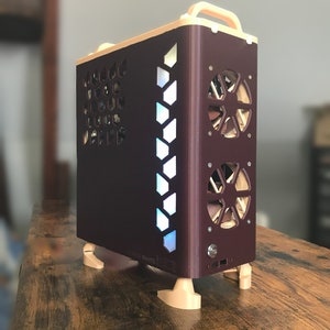 Puede incluir: Una caja de ordenador personalizada con un exterior marrón y detalles beige. La caja tiene un panel lateral con un patrón de panal de abeja, un panel transparente con un diseño geométrico y dos ventiladores en la parte posterior.