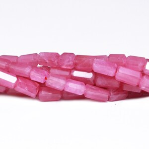 May include: A strand of pink gemstone beads, each bead is faceted and has a rectangular shape.