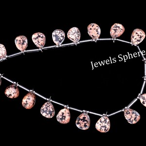 May include: A strand of gemstone beads with a silver-toned metal wire. The beads are a clear quartz with copper inclusions, and they are in a teardrop shape. The strand is labelled "Jewels Sphere".