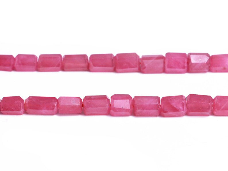 May include: A strand of pink faceted gemstone beads. The beads are rectangular in shape and have a smooth, polished finish.