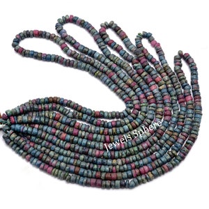 May include: A strand of blue, green, and pink gemstone beads. The beads are small and round, and they are strung together on a clear thread. The beads are arranged in a loose, flowing pattern.