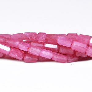 May include: A strand of pink gemstone beads, each bead is faceted and has a rectangular shape.