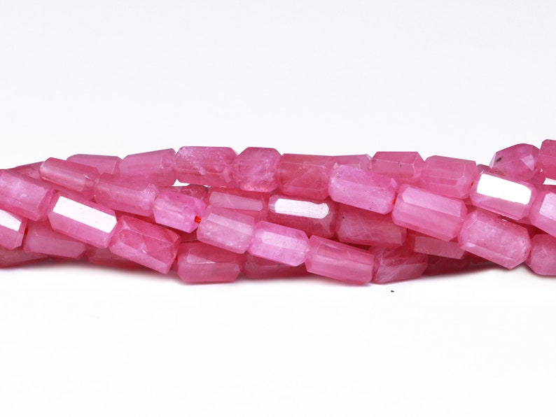 May include: A strand of pink gemstone beads, each bead is faceted and has a rectangular shape.