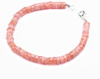 May include: A pink gemstone bracelet with a silver clasp. The bracelet is made of small, square-shaped beads.