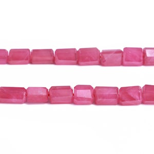 May include: A strand of pink faceted gemstone beads. The beads are rectangular in shape and have a smooth, polished finish.