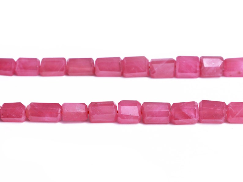 May include: A strand of pink faceted gemstone beads. The beads are rectangular in shape and have a smooth, polished finish.