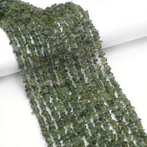 May include: A strand of green gemstone chips, also known as green aventurine, for jewelry making. The chips are irregular in shape and have a natural, earthy look.