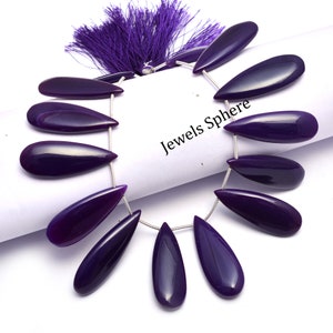 Könnte beinhalten: Eine Kette aus violetten Achat-Edelsteinen in Tropfenform. Die Perlen sind auf einem Silberdraht aufgefädelt und haben einen Quasten am Ende. Die Perlen sind kreisförmig angeordnet und der Text "Jewels Sphere" ist auf dem Bild zu sehen.