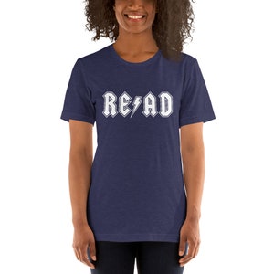 May include: A navy blue t-shirt with a white graphic that says "READ" in a rock and roll font with a lightning bolt.
