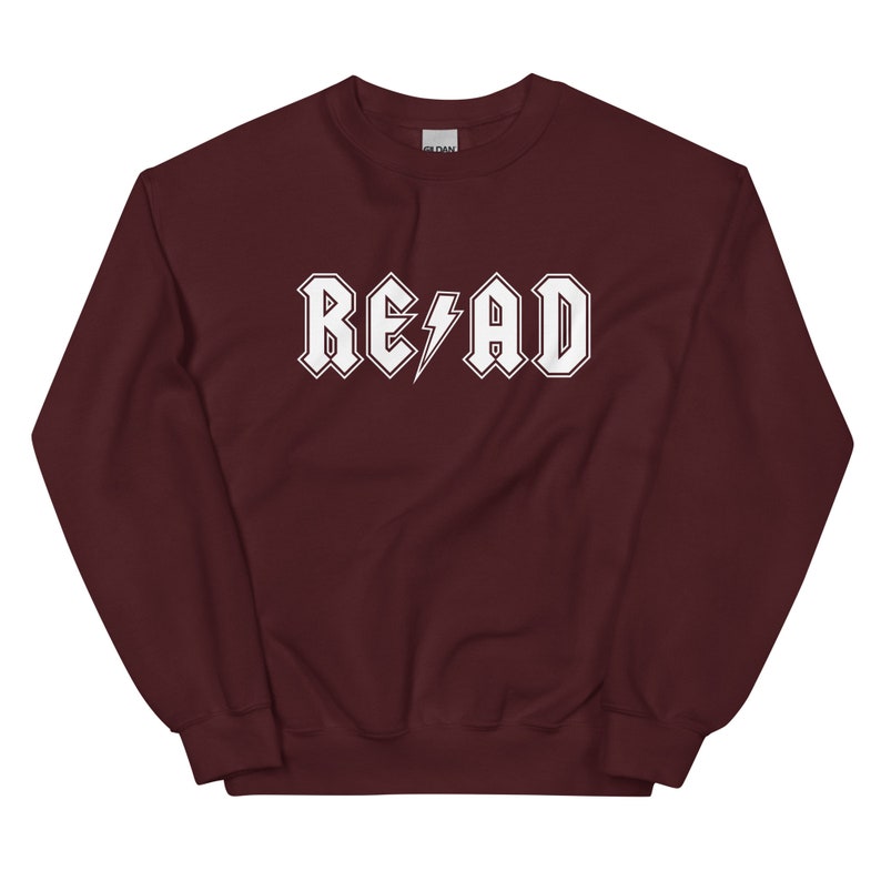 Puede incluir: Sudadera color burdeos con un gr&aacute;fico blanco que dice "RE/AD" con un rayo en lugar de la barra oblicua.