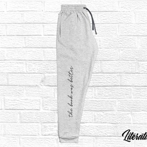May include: Gray sweatpants with the text "the book was better" printed on the side. The sweatpants have a black drawstring.