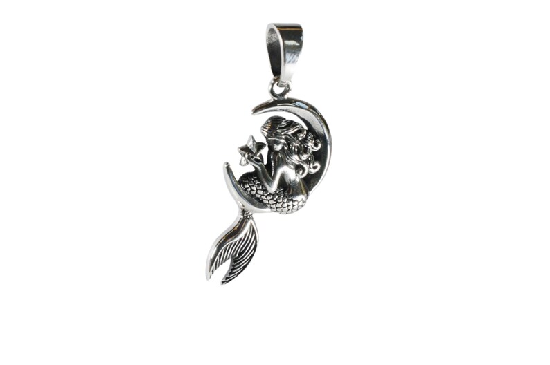 May include: A silver pendant featuring a mermaid sitting on a crescent moon, holding a star. The mermaid has a detailed tail and flowing hair.