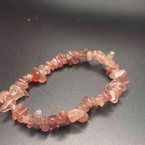 Pode incluir: Um bracelete de lascas de cristal rosa e transparente. O bracelete é feito de pequenas lascas de cristal de forma irregular.