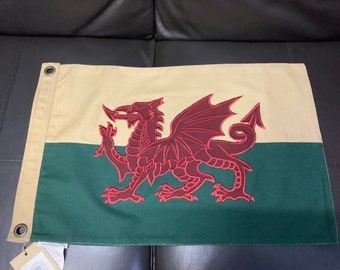Puede incluir: Una bandera galesa con un dragón rojo sobre un fondo blanco y verde. El dragón está bordado y tiene un diseño detallado.