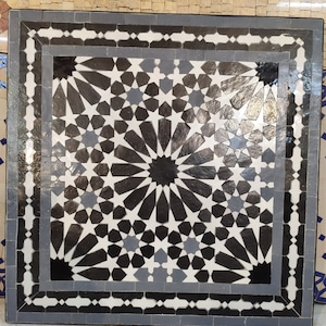 May include: A square black and white mosaic tile table top with a geometric pattern of stars and a gray border.