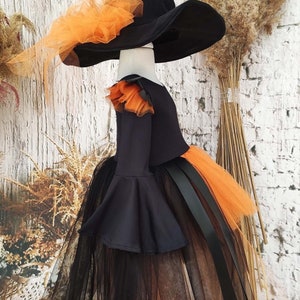 This witch costume for girls features a stylish design with black leather accents, black orange tulle, and a unique high-low hem, making it perfect for Halloween and special occasions