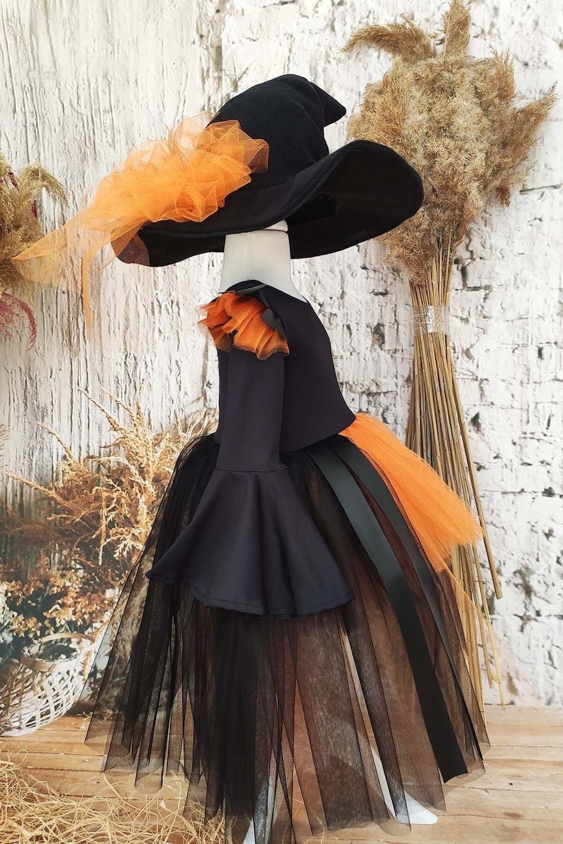 This witch costume for girls features a stylish design with black leather accents, black orange tulle, and a unique high-low hem, making it perfect for Halloween and special occasions