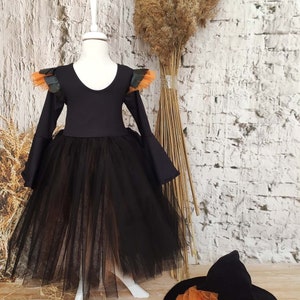 This witch costume for girls features a stylish design with black leather accents, black orange tulle, and a unique high-low hem, making it perfect for Halloween and special occasions