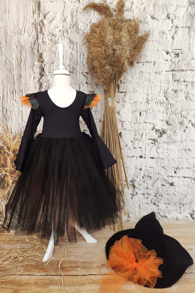 This witch costume for girls features a stylish design with black leather accents, black orange tulle, and a unique high-low hem, making it perfect for Halloween and special occasions