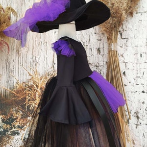 This enchanting toddler witch costume is perfect for girls looking to embrace Halloween in style. It features a black and orange asymmetrical gothic tutu dress and a matching witch hat.