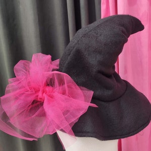 May include: A black witch hat with a large pink tulle bow. The hat is made of felt and has a pointed crown.