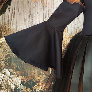 This witch costume for girls features a stylish design with black leather accents, black orange tulle, and a unique high-low hem, making it perfect for Halloween and special occasions