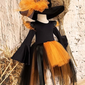 This witch costume for girls features a stylish design with black leather accents, black orange tulle, and a unique high-low hem, making it perfect for Halloween and special occasions