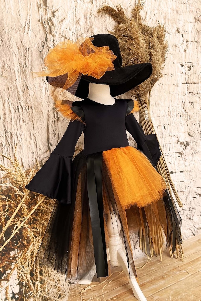 This witch costume for girls features a stylish design with black leather accents, black orange tulle, and a unique high-low hem, making it perfect for Halloween and special occasions