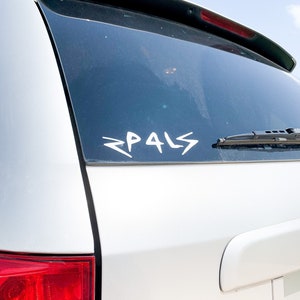 Puede incluir: Un coche blanco con una luneta trasera negra y una pegatina de vinilo blanco que dice "PALS" en la luneta trasera.