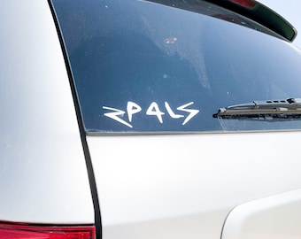 Può includere: Un'auto bianca con un lunotto posteriore nero e un adesivo in vinile bianco che dice "PALS" sul lunotto posteriore.