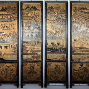 Puede incluir: Una pantalla de cuatro paneles con intrincadas escenas pintadas en oro y negro de un jardín chino. Cada panel presenta una escena diferente con figuras, edificios y paisajes. La pantalla está hecha de madera y está en excelente estado.