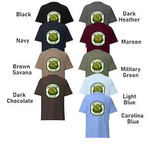 Puede incluir: Una maqueta de una camiseta con un gr&aacute;fico de monstruo verde y el texto "Emotional Support Nurling". La camiseta est&aacute; disponible en 10 colores diferentes: negro, azul marino, marr&oacute;n savana, chocolate oscuro, gris oscuro, marr&oacute;n, verde militar, azul claro y azul carolina.