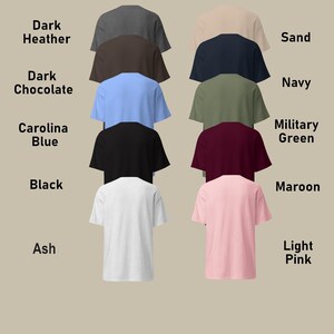 May include: A collection of short-sleeve t-shirts in various colors, including dark heather, dark chocolate, Carolina blue, black, ash, sand, navy, military green, maroon, and light pink. Each shirt is displayed with its color name.