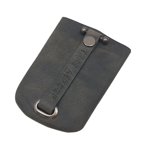 Könnte beinhalten: Ein dunkelgrauer Leder-Schlüsselanhänger mit einer Metallschlaufe und einem schwarzen Lederband mit dem geprägten Text "JOCKEY CLUB".
