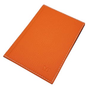 Könnte beinhalten: Ein orangefarbenes Notizbuch aus Leder mit weißen Nähten an den Rändern. Das Notizbuch hat eine strukturierte Oberfläche und ein kleines Logo in der unteren rechten Ecke. Der Einband ist einfarbig, leuchtend orange.