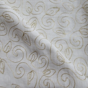 May include: White fabric with a gold embroidered pattern of swirling vines and leaves.