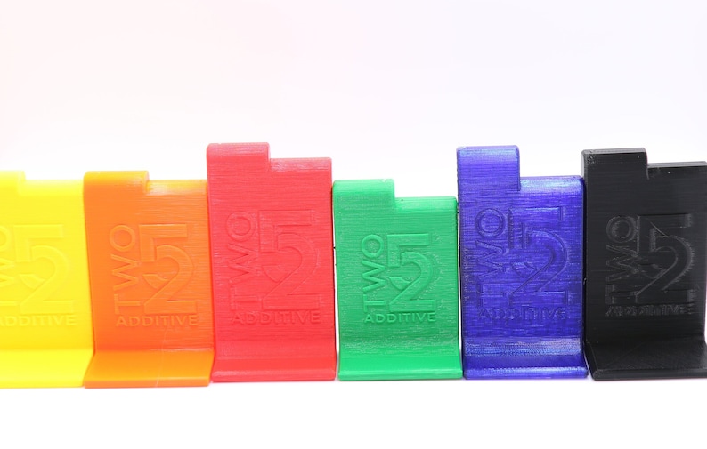 May include: Six colorful plastic blocks with the text "TWO 52 ADDITIVE" printed on each. The blocks are arranged in a row from left to right in the following order: yellow, orange, red, green, blue, and black.