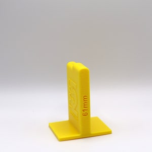 May include: A yellow plastic spacer block with the text "61mm" printed on the side. The block has a square base and a rectangular top.