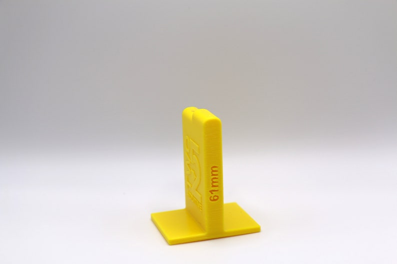 May include: A yellow plastic spacer block with the text "61mm" printed on the side. The block has a square base and a rectangular top.