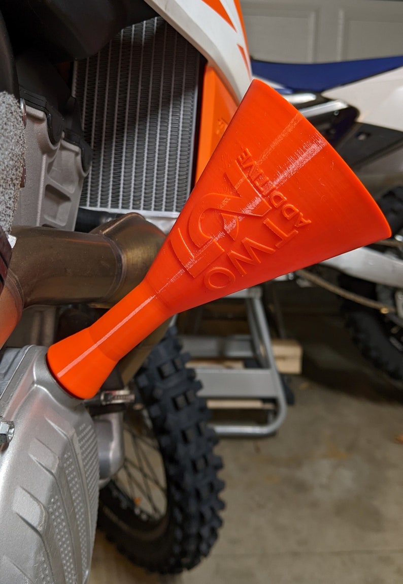 May include: Orange plastic funnel with the text "ONE WAY" printed on the side. The funnel is attached to a motorcycle.