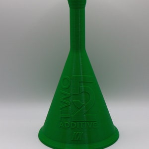 May include: A green plastic bottle with a wide base and a narrow neck. The bottle has the text "TWO 52 ADDITIVE" printed on the side.