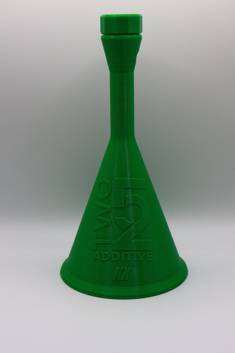 May include: A green plastic bottle with a wide base and a narrow neck. The bottle has the text "TWO 52 ADDITIVE" printed on the side.