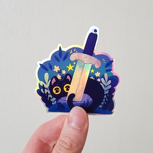 May include: A black cat with yellow eyes peeks out from behind a holographic iridescent sword, surrounded by blue and purple flowers and stars.
