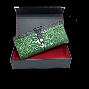 a green alligator skin wallet in a black box