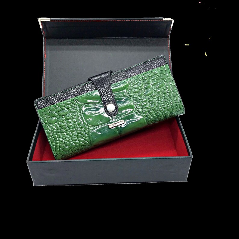 a green alligator skin wallet in a black box