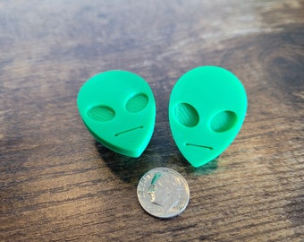 May include: Two green alien face guitar picks. The picks are about the size of a US dime.